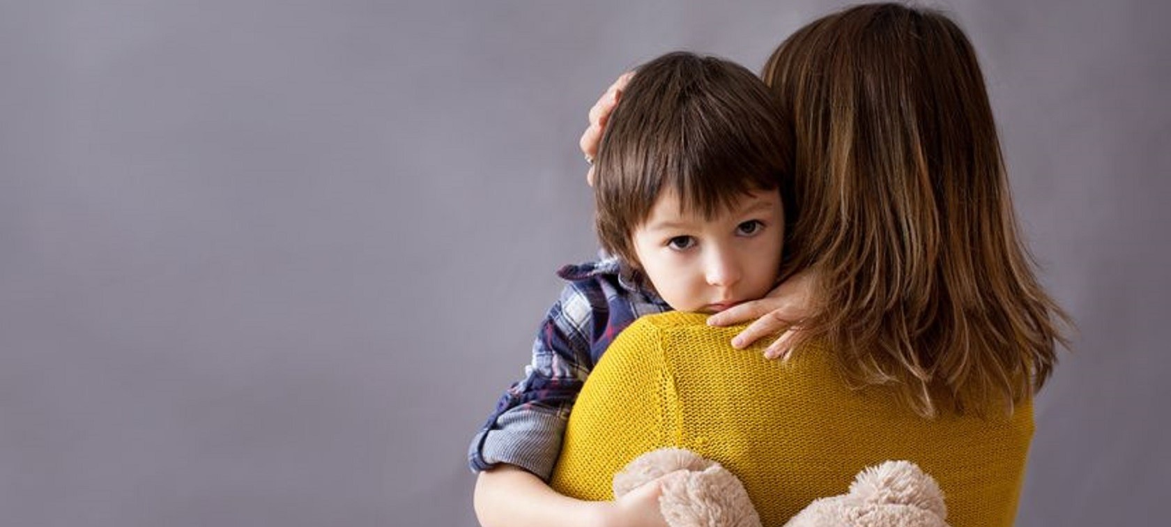 Mutter hält traurigen Jungen mit Teddy im Arm Mutter hält traurigen Jungen mit Teddy im Arm